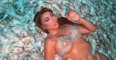 Kali Uchis lays on a bed of money