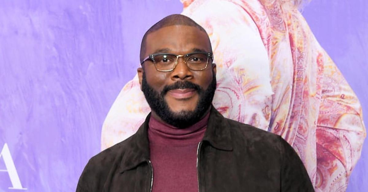 Tyler Perry is wearing a maroon turtle neck with a brown jacket.