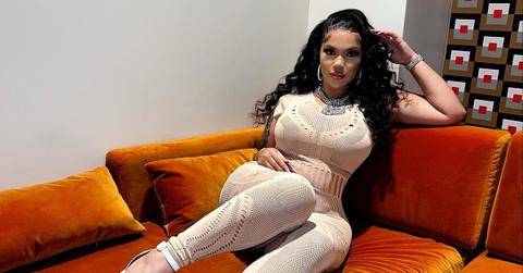 Renni Rucci poses on an orange couch.